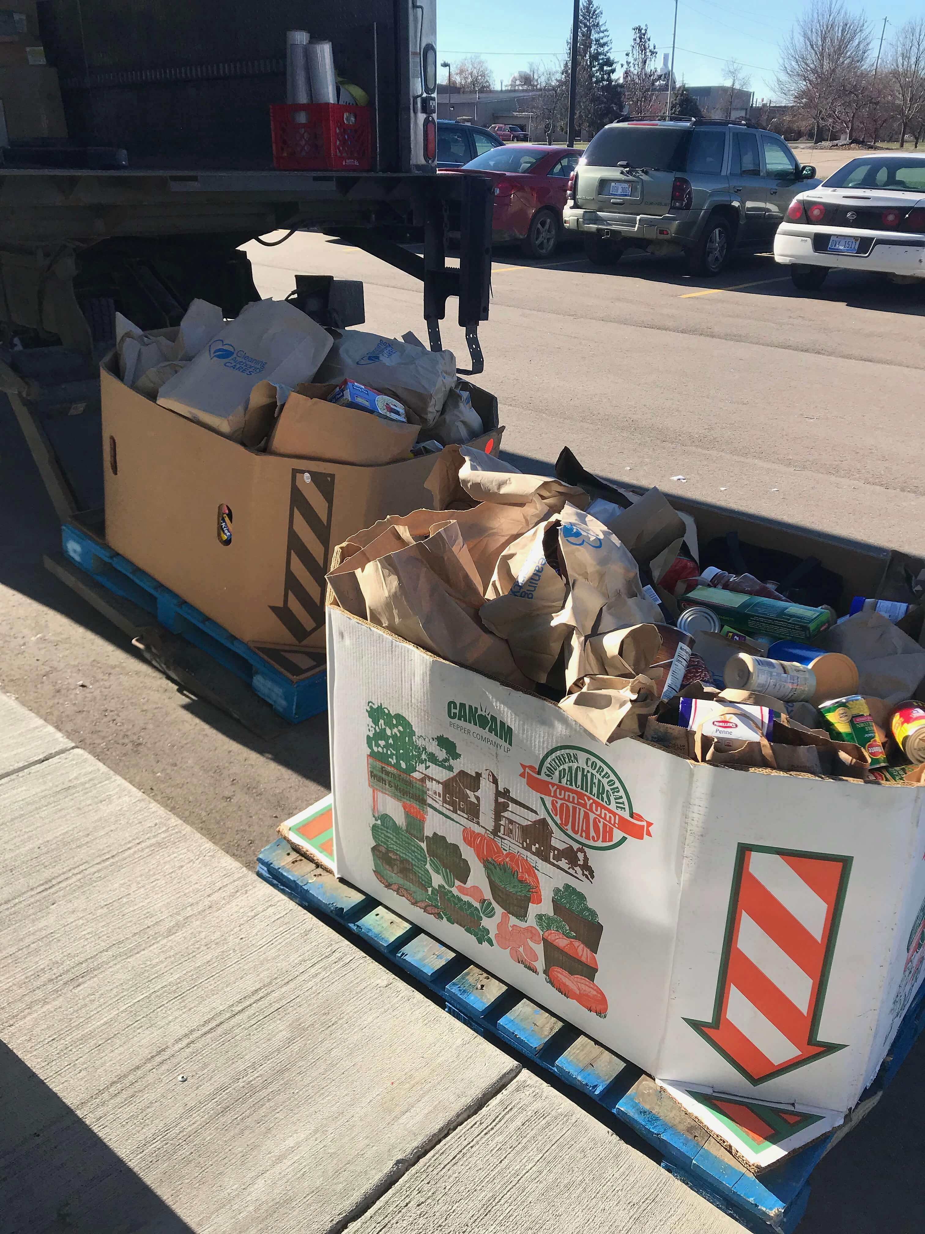 Two cardboard boxes full of food donations gathered by the TCA Fenton team sit on wooden pallets.