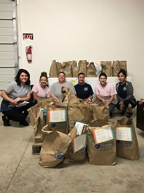 The TCA Fishers team poses with the food donations collected for local charities.