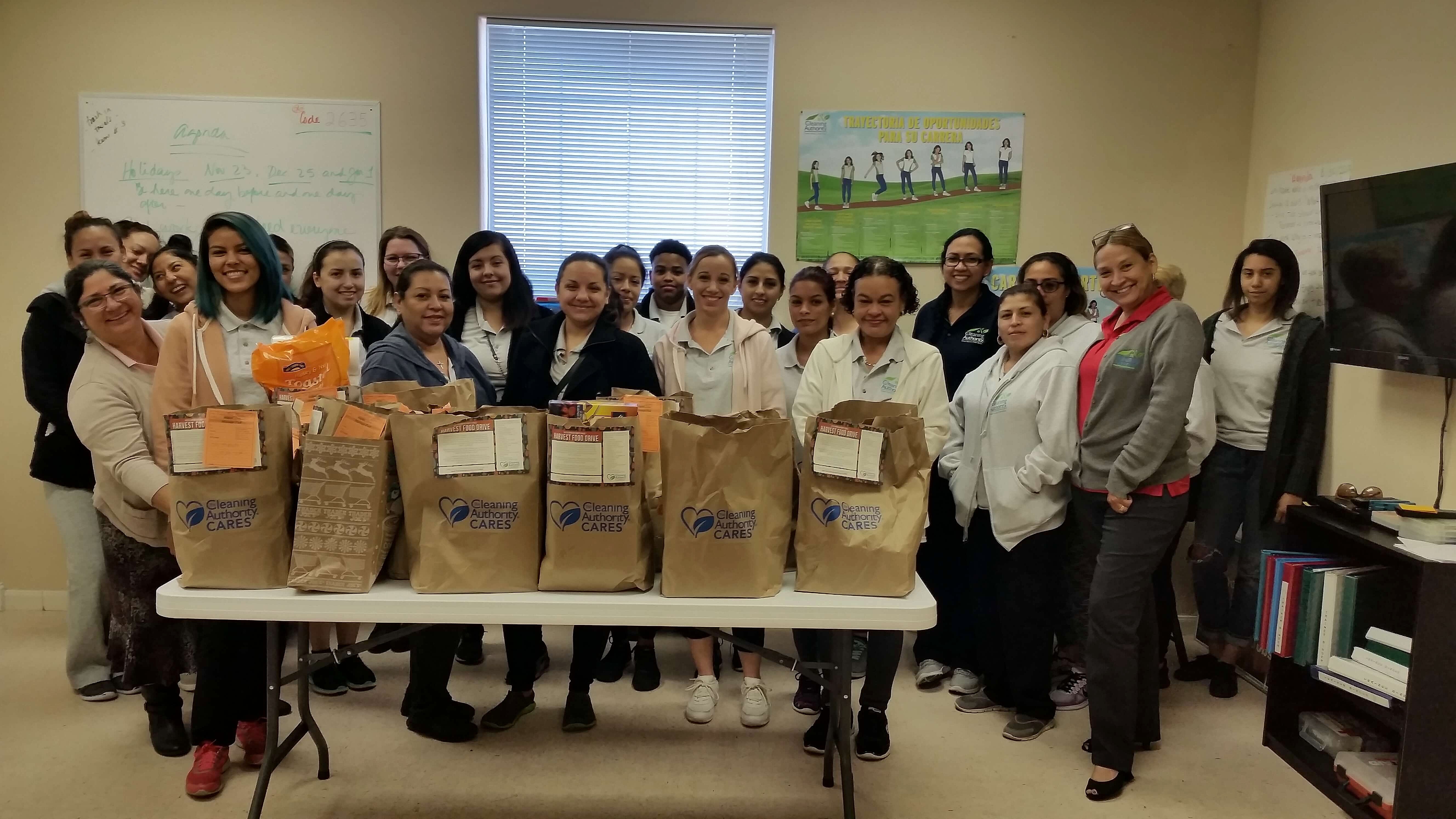 The TCA San Antonio team stands in their office with donations collected for a local charity.